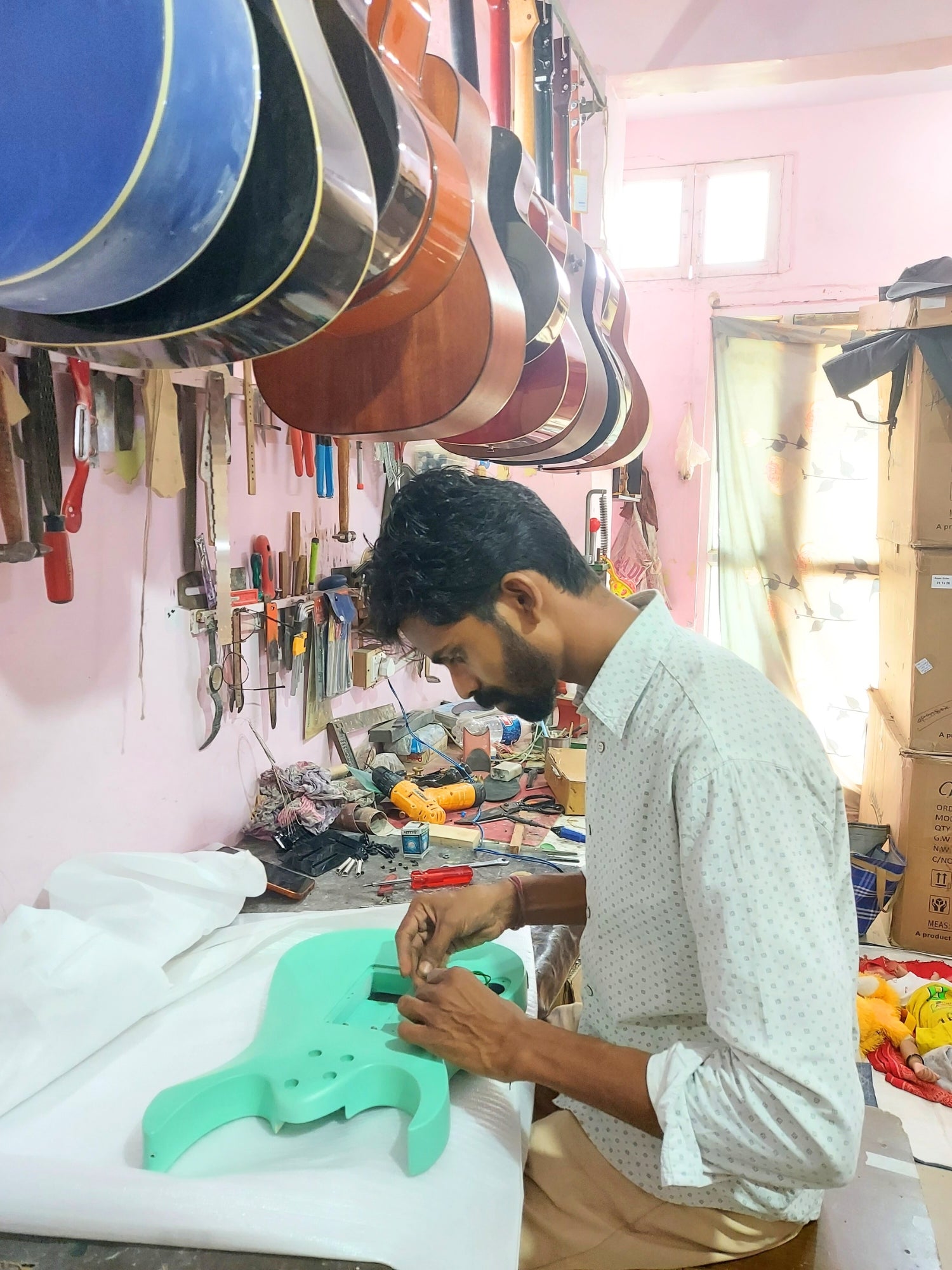 Guitar Technician Repairing an electric guitar with multiple guitars & parts displayed in the background