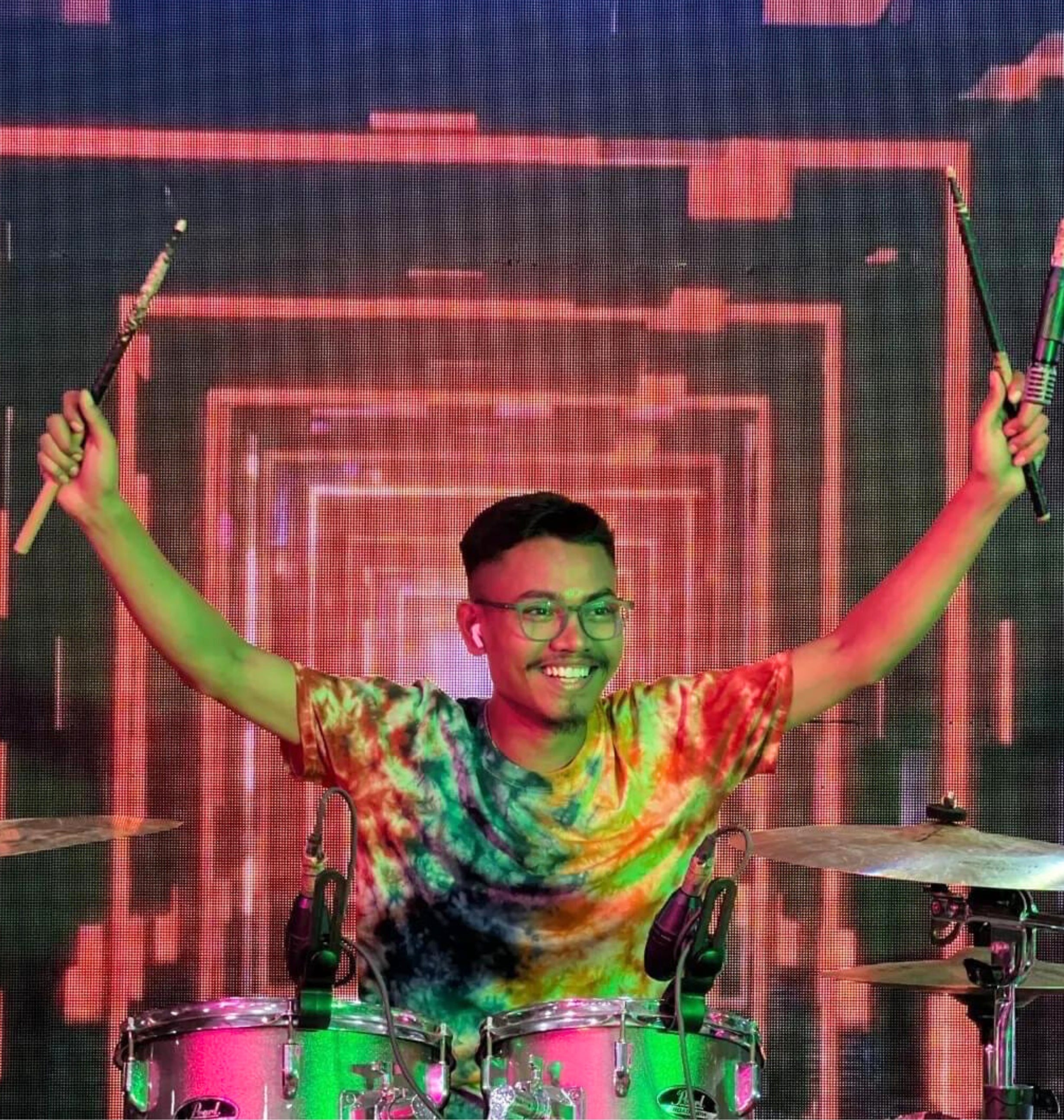 A stage performed named 'Amit Thomas' playing drums set in a show