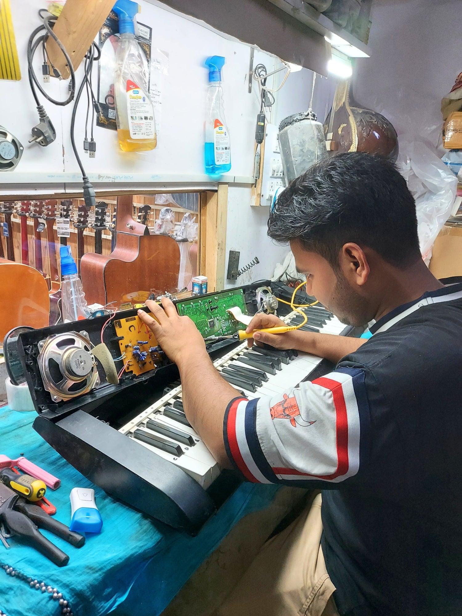 Keyboard Technician repairing a keyboard with multiple keyboard parts displayed in the background